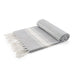 The Chandon Escape - A grey blanket with white stripes and fringed edges, neatly rolled and displayed. It has a simple, elegant design.