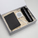 The Daily Setup - A black drink bottle, notebook, white speaker, and pen in a gift box with shredded paper filling.