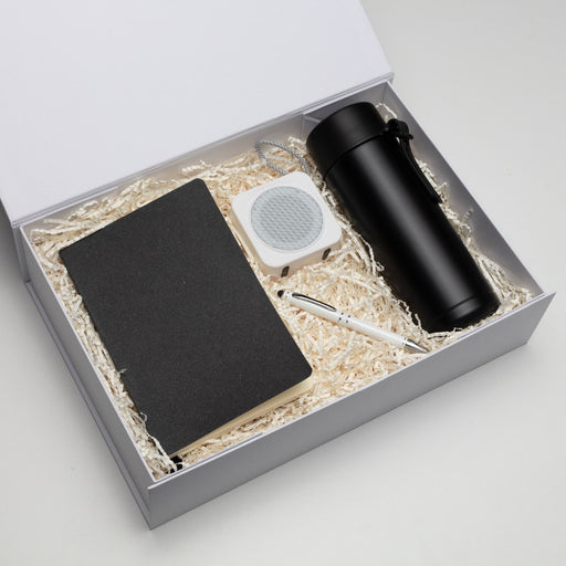The Daily Setup - A black drink bottle, a notebook, a white speaker, and a pen packed in a gift box with shredded paper.