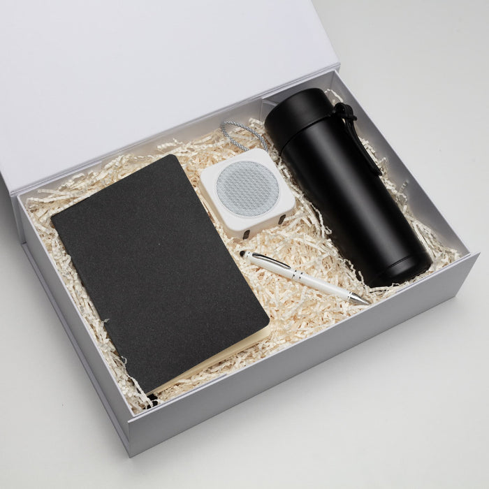 The Daily Setup - A black drink bottle, a notebook, a white speaker, and a pen packed in a gift box with shredded paper.