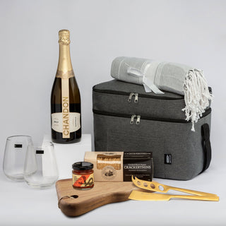 The Chandon Escape - A grey cooler bag with a blanket, two glasses, a bottle of Chandon, a cheese board, and gourmet products inside.