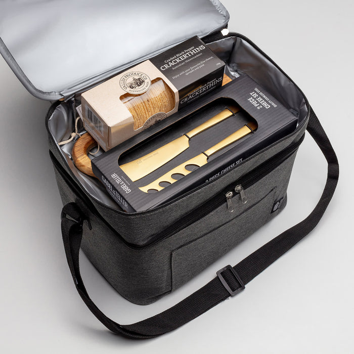 The Chandon Escape - A grey insulated hamper with a wooden cheese board, utensils, and snacks inside, featuring a logo on the exterior.