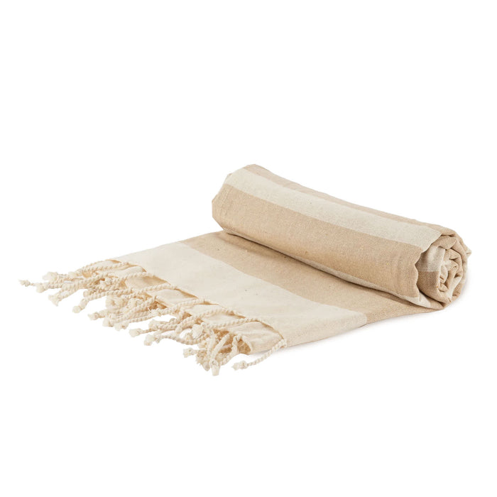 The Sunchaser Set - A rolled beige and cream striped picnic blanket with fringed edges, featuring a simple design. It has a logo.