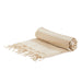 The Sunchaser Set - A rolled beige and cream striped picnic blanket with fringed edges, featuring a simple design. It has a logo.