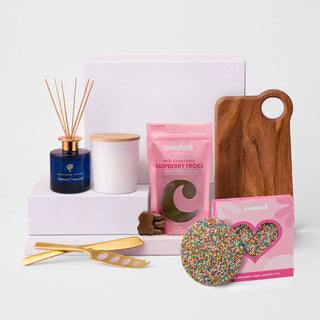 The Generous Host - A selection of gift items including a blue candle, a wooden board, raspberry frogs, and a sprinkles-covered cookie.