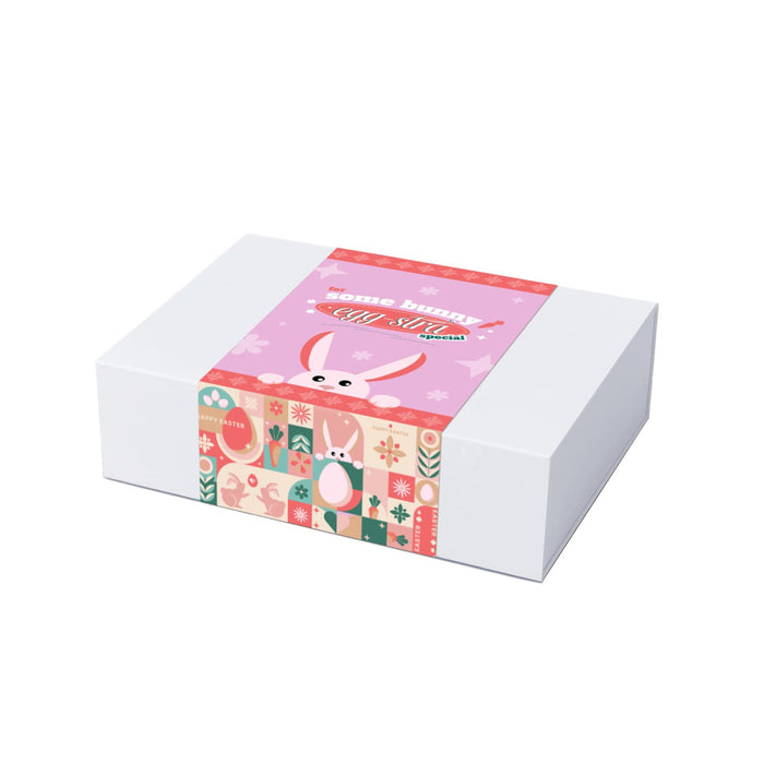 The Generous Host - A gift box with a pastel pink design featuring bunny illustrations and decorative patterns, secured with a printed band.