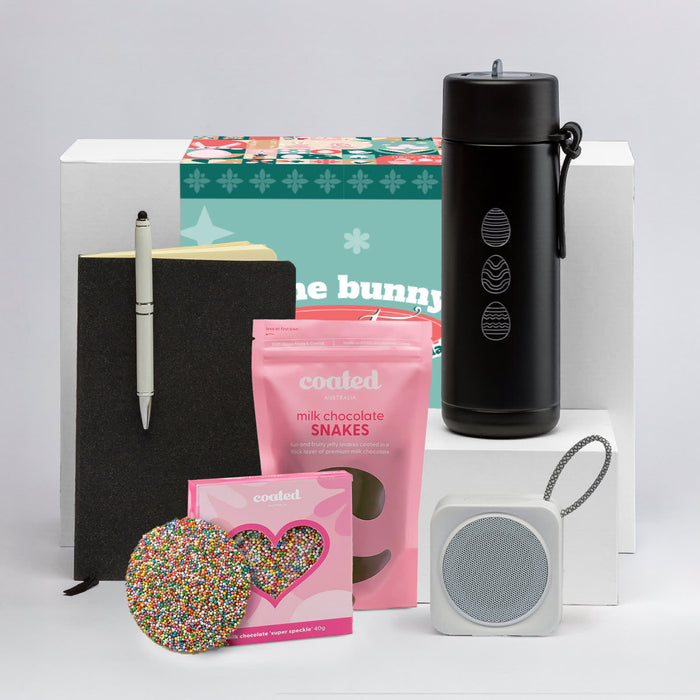 The Sweet Setup - A black drink bottle, a notebook, a pen, chocolate snakes, a heart-shaped sprinkles cookie, and a speaker.