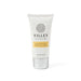 The Mindful Moment - A hand and nail cream tube in white and silver, featuring a floral logo and a yellow label.