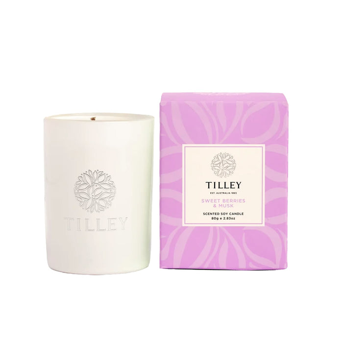 The Mindful Moment - A white scented soy candle is accompanied by a purple box, labelled "Sweet Berries & Musk", featuring a logo.