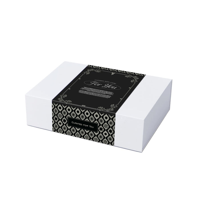 The Glow & Graze: Christmas Edition - A gift box featuring a black and white patterned design, wrapped with a decorative band.