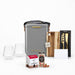 The Festive Edit Gift Set - A grey insulated bag, two clear glasses, a wooden cheese knife, a gift box, and festive snacks.