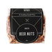 The Big Indulge - A clear plastic bag containing roasted beer nuts, showcasing a mix of light brown and tan nuts. The bag features a black label with branding.
