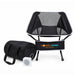 The Escape Pack - A portable black camping chair with a mesh back, accompanied by a black storage bag and a small speaker.