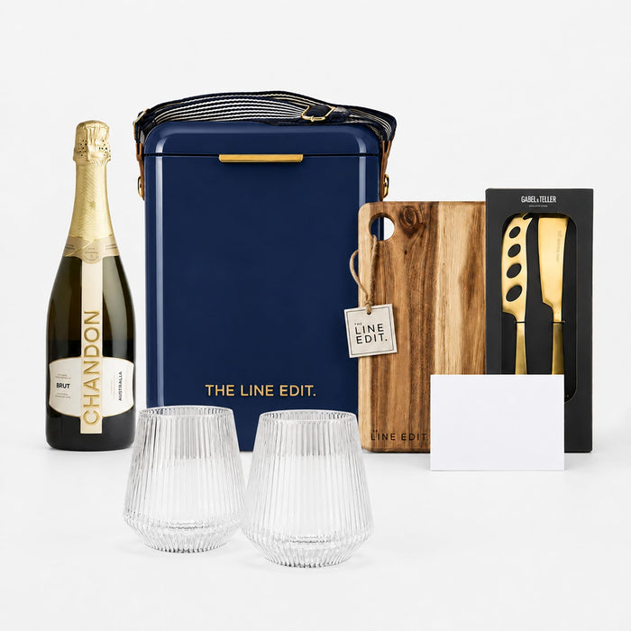 The Pour & Gather Hamper - A navy hamper with a drink bottle, two crystal glasses, a wooden board, a corkscrew, and a card. It features branding.