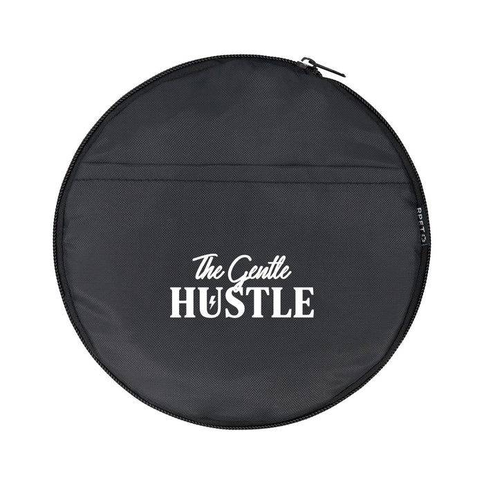 The Hustle Pack - A round black bag with a zip, featuring a logo and the words "The Gentle Hustle" in white.