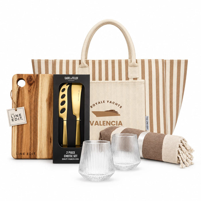 The Weekend Edit - A tote bag with stripes, a wooden cheese board, a two-piece cheese set, two textured glasses, and a striped blanket.