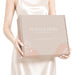 Custom Box with Locking Lid 360 x 305 x 105mm - A light beige box with a locking lid, featuring floral motifs and a logo, held by a person in a satin dress.
