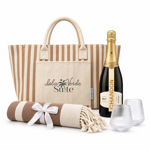 The Sun & Sip Gift Set - A striped tote bag, a champagne bottle, two glasses, and a blanket with a bow, all in neutral tones.