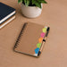 Calton Sticky Note Memo - A brown spiral notebook sits on a wooden surface, accompanied by a pen and vibrant sticky notes in various colours.