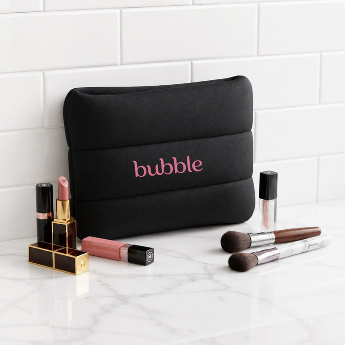 Bubble Neoprene Cosmetic Bag - A black neoprene cosmetic bag with pink branding, surrounded by various lip products and makeup brushes.
