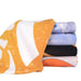 Bath Sheet - A set of colourful face washers stacked together, featuring orange, blue, black, and white patterns.