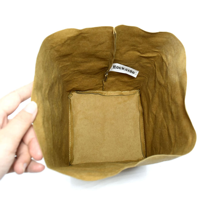 Sewo Kraft Paper Storage Bag – Large - A large brown kraft paper storage bag with a squared base and a logo inside. The bag is held by a hand.