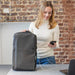 Swissdigital Arosa Backpack - A grey Swissdigital Arosa Backpack with a logo, placed beside a laptop, while a person is using a smartphone.