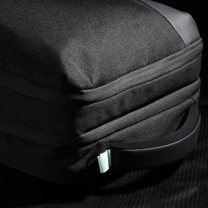 Swissdigital Arosa Backpack - A black backpack with a textured exterior and a mint green zipper pull, featuring a side handle.