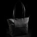 Swissdigital Arosa Tote Bag - A black tote bag with leather handles and a front pocket, featuring a logo on the side.