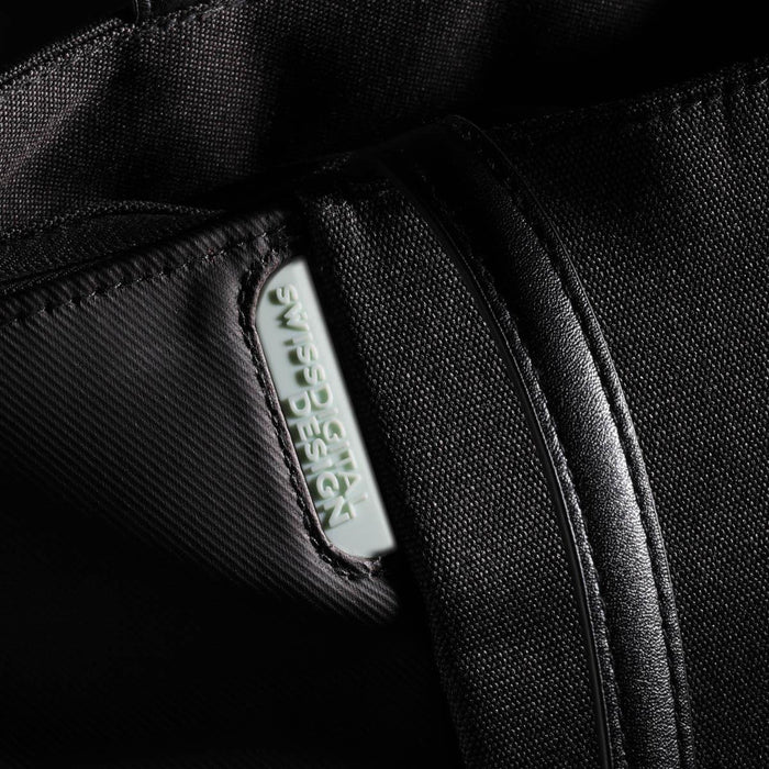 Swissdigital Arosa Tote Bag - A black tote bag with a zipper and a prominent logo tag features a sleek, minimalist design.