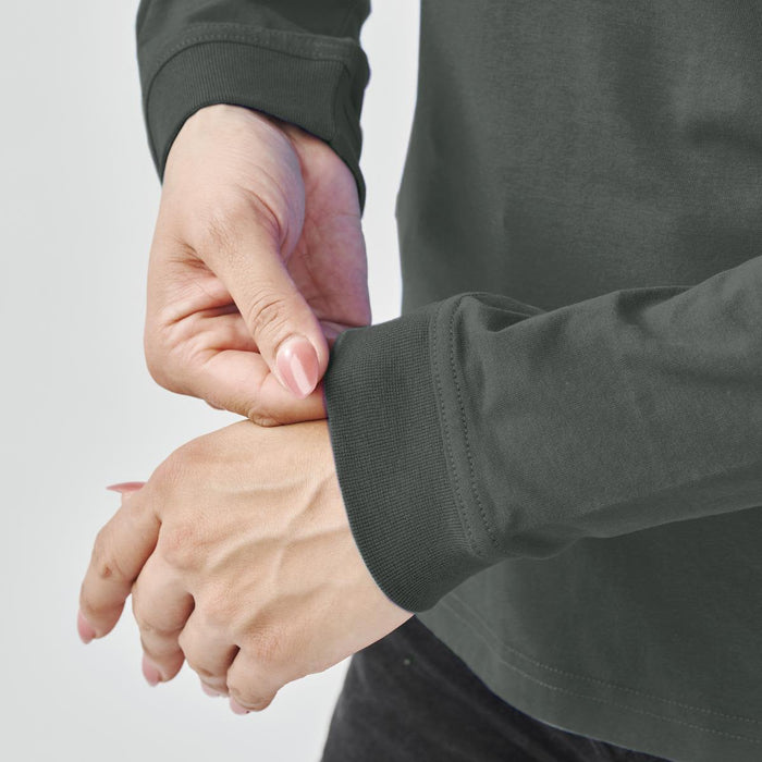 Women's Settebello L/S Tee - A close-up of a person adjusting the cuff of a dark green long-sleeve t-shirt featuring a logo.