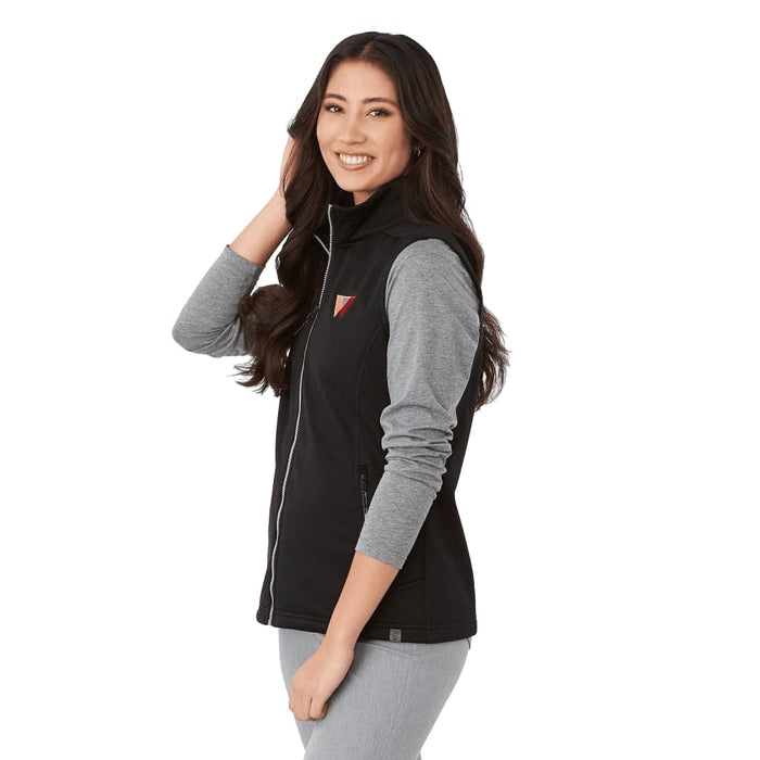 Women's Joris Eco Waterproof Softshell Vest - A woman wearing a black and grey eco waterproof softshell vest with a logo. The vest features a zip front and side pockets.