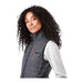 Women's Telluride Lightweight Packable Insulated Puffer Vest - A woman with curly hair wears a black insulated puffer vest, featuring a logo on the chest.