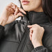 Women's Sierra Thermal Jacket - A woman zips up a black puffer jacket with a high collar, showcasing the thermal design.